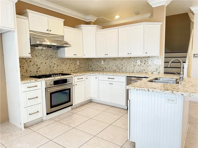 a kitchen with stainless steel appliances granite countertop a stove a sink and a refrigerator