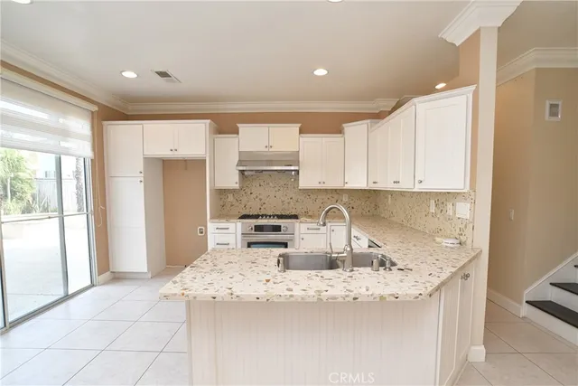 a kitchen with granite countertop a sink a stove and a refrigerator
