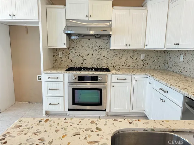 a kitchen with granite countertop white cabinets and stainless steel appliances