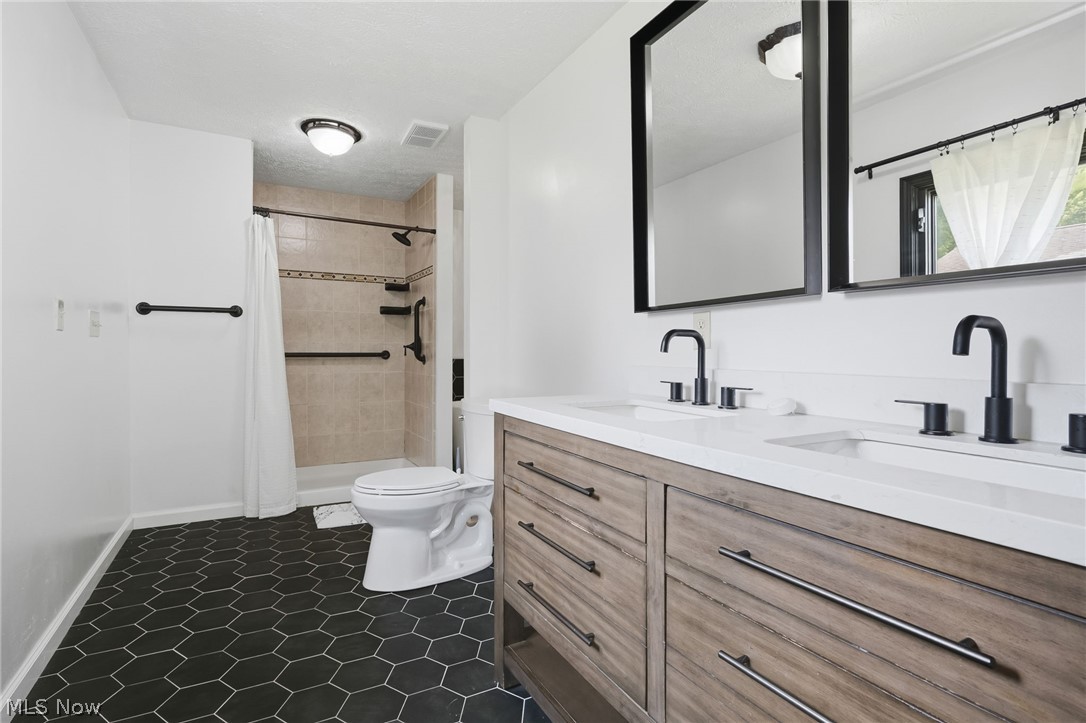 8160 Joyce Road Broadview Heights, OH 44147 - Photo 25 of 45 Bathroom featuring a double vanity with wood-finish cabinetry, white countertops, and matte black fixtures