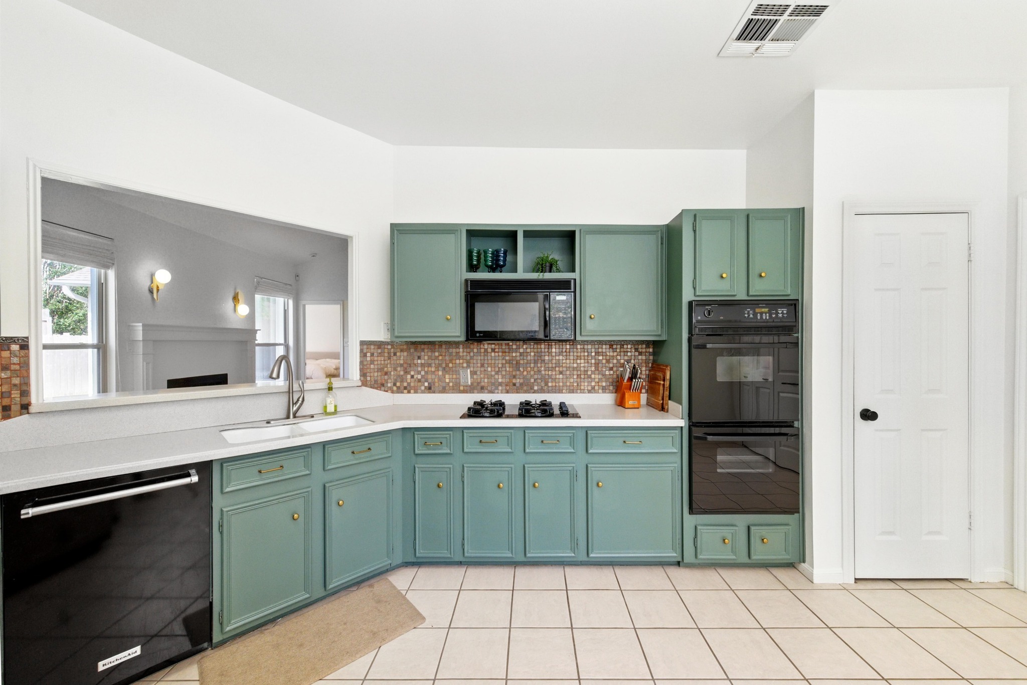 5807 Convict Hill Road Austin, TX 78749 - Photo 13 of 27 Framed by rich backsplash tile and stylish green cabinets, this kitchen is both cozy and functional. A look through the passthrough reveals the light-filled living room fireplace.