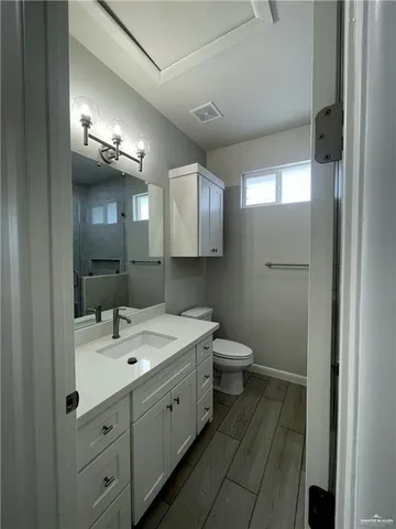 a bathroom with a double vanity sink and mirror with toilet