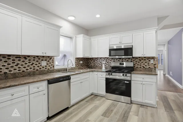 a kitchen with granite countertop white cabinets and black stainless steel appliances