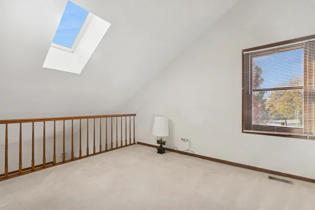 an empty room with chandelier fan and windows