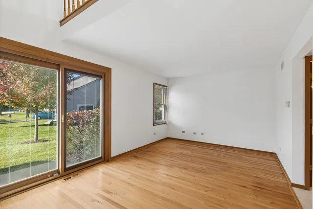 a view of an empty room with wooden floor and stairs