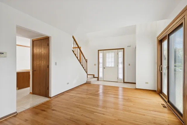 a view of an empty room with wooden floor and stairs