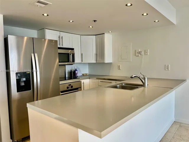 a kitchen with stainless steel appliances granite countertop a refrigerator a sink a stove a microwave and a refrigerator