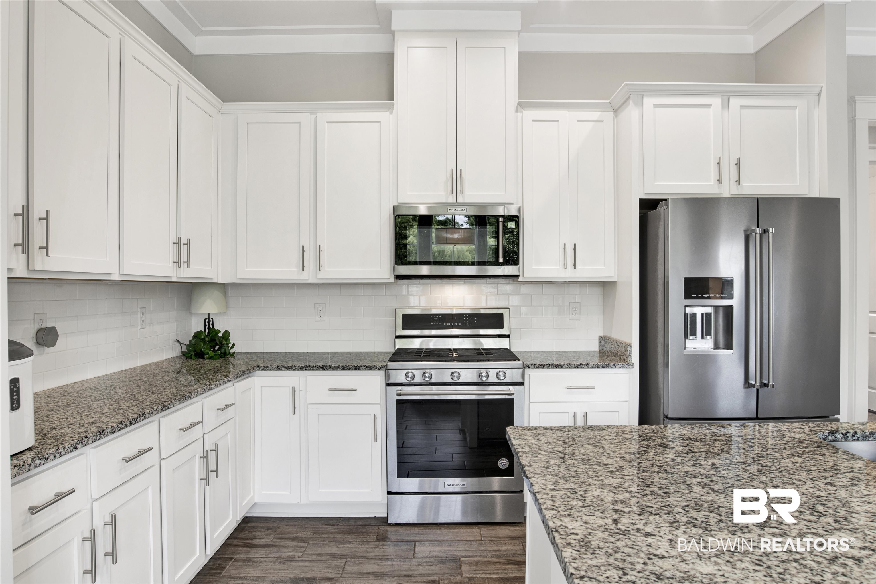 23893 Cypress Crossing Orange Beach, AL 36561 - Photo 6 of 22 Kitchen with stainless steel appliances, white cabinets, ornamental molding, dark stone countertops, and tasteful backsplash
