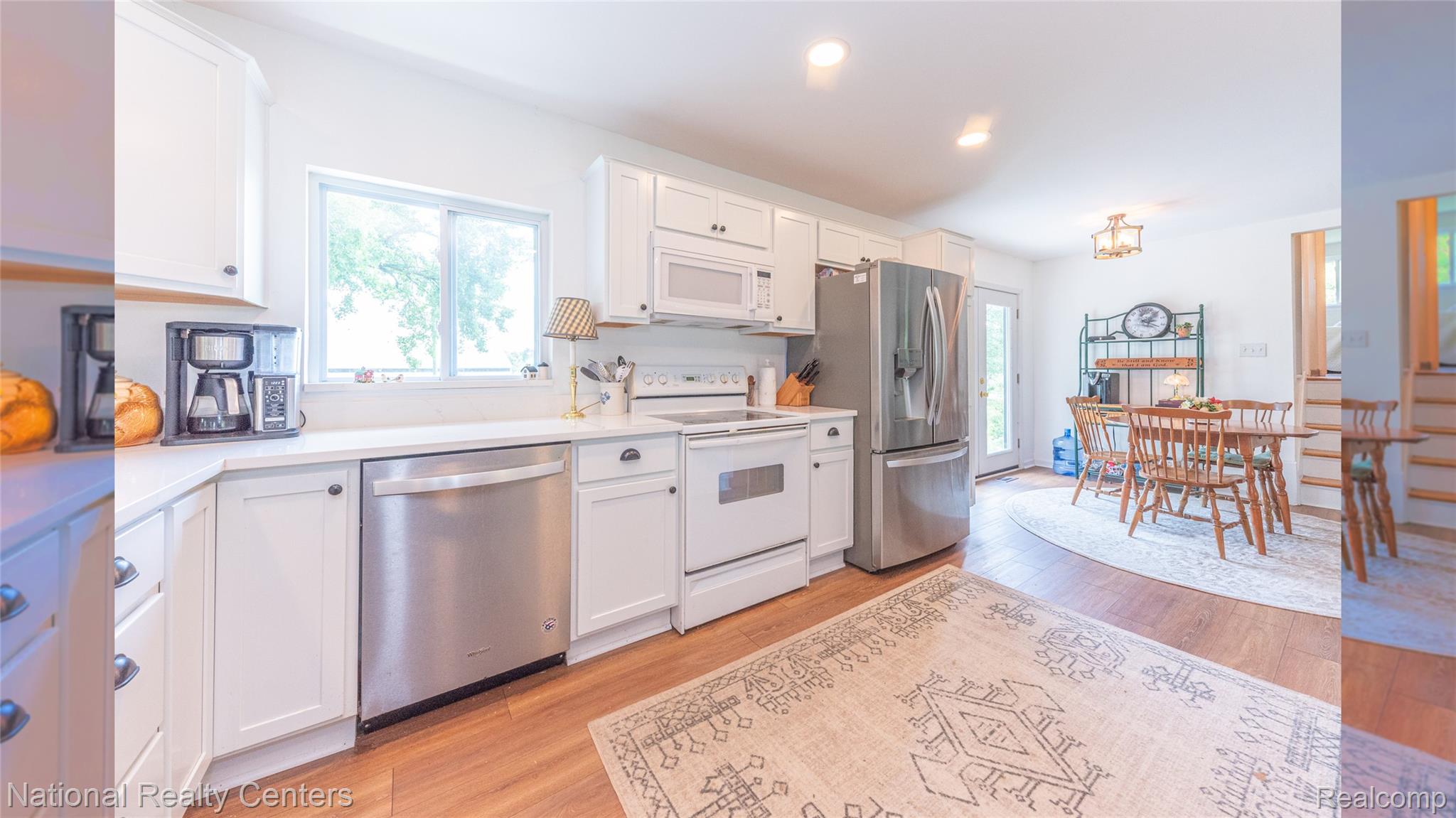 58191 8 Mile Road Northville, MI 48167 - Photo 32 of 57 Light-filled kitchen featuring white cabinetry, light-toned countertops, and stainless steel appliances including a refrigerator, dishwasher, and microwave
