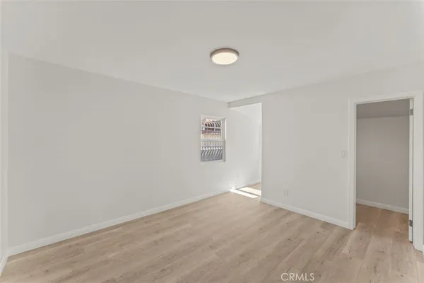 a view of an empty room with wooden floor and closet