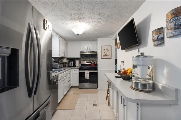 a kitchen with stainless steel appliances a sink a stove a refrigerator cabinets and a counter top space