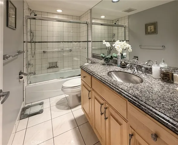 a bathroom with a granite countertop sink a toilet and shower