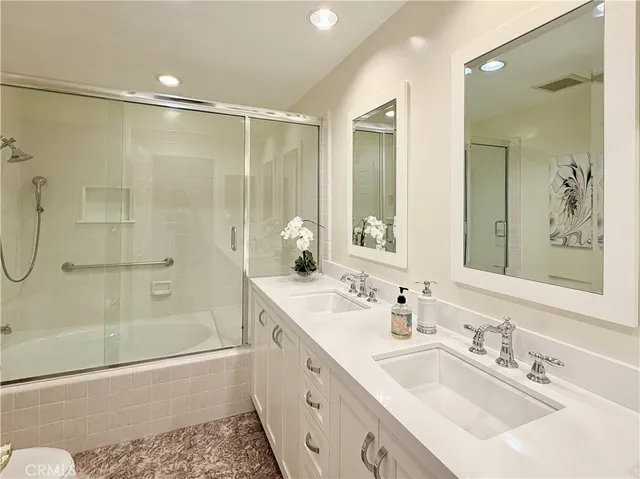 a bathroom with a tub sink double vanity and shower