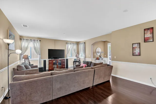 a living room with furniture two large windows and a flat screen tv