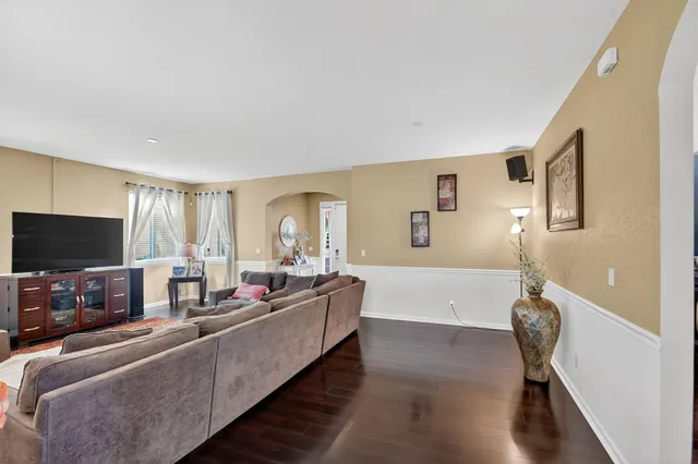 a kitchen with stainless steel appliances kitchen island granite countertop a stove top oven a sink a dining table and chairs with wooden floor