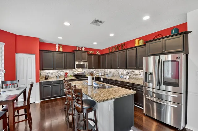 a kitchen with stainless steel appliances granite countertop a stove top oven a sink and a dining table with chairs