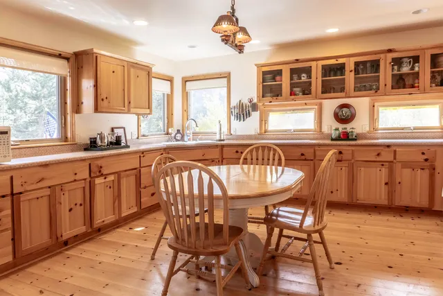 a kitchen with stainless steel appliances granite countertop a table chairs sink and cabinets