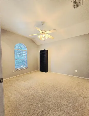 an empty room with a chandelier fan and windows