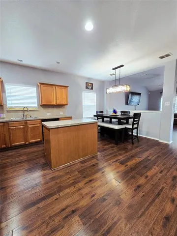 a kitchen with stainless steel appliances kitchen island granite countertop wooden floors and a view of living room