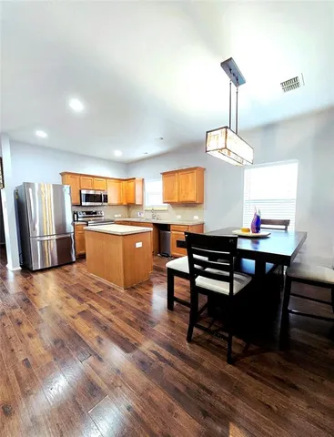 a view of a kitchen with a dining table chairs wooden floor and a ceiling fan