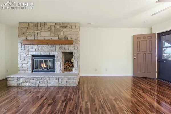 a view of an empty room with wooden floor fireplace and a window