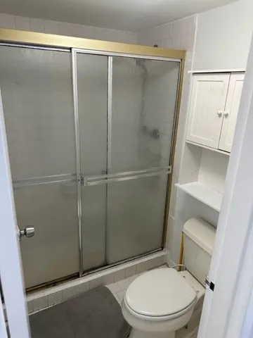 a white toilet sitting next to a shower