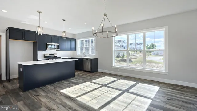 a kitchen with stainless steel appliances granite countertop a refrigerator a sink dishwasher a stove and white cabinets with wooden floor