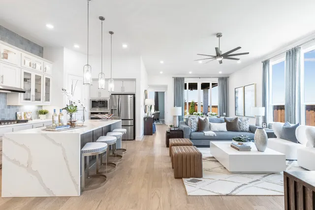 a living room with furniture kitchen area and a chandelier