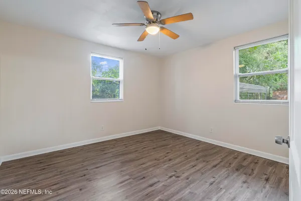 a view of an empty room with wooden floor and a window