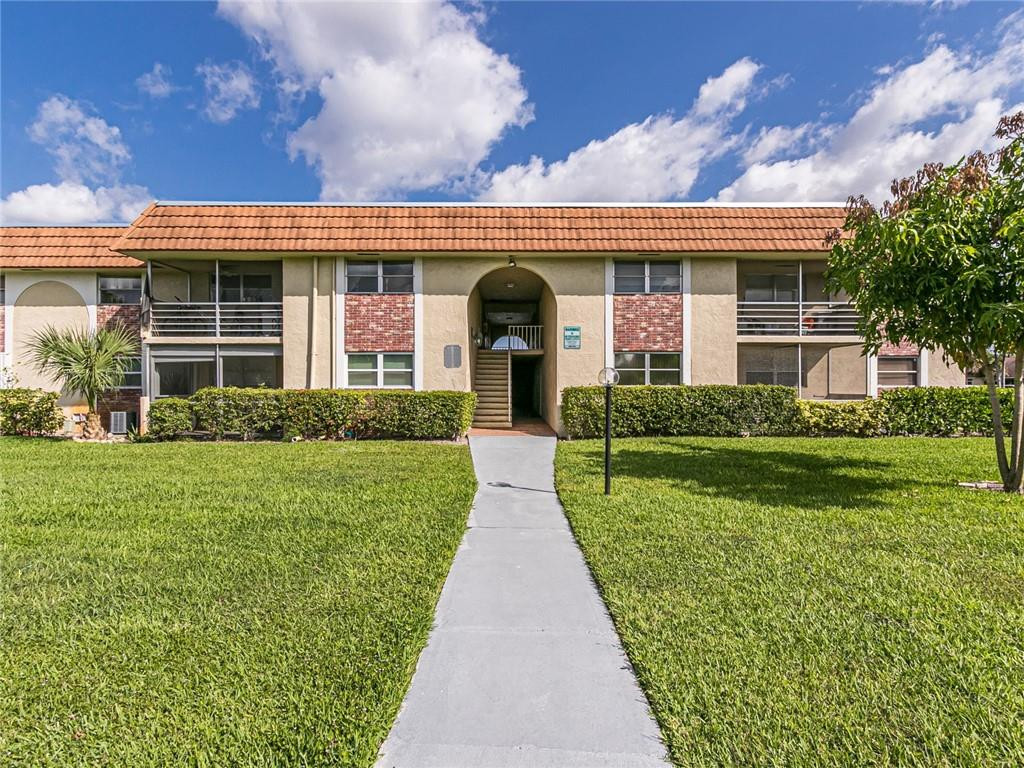 22735 Southwest 66th Avenue, Unit 202 Boca Raton, FL 33428 - Photo 27 of 30 a front view of a house with a yard and potted plants