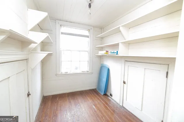 a view of an empty room with wooden floor and a window