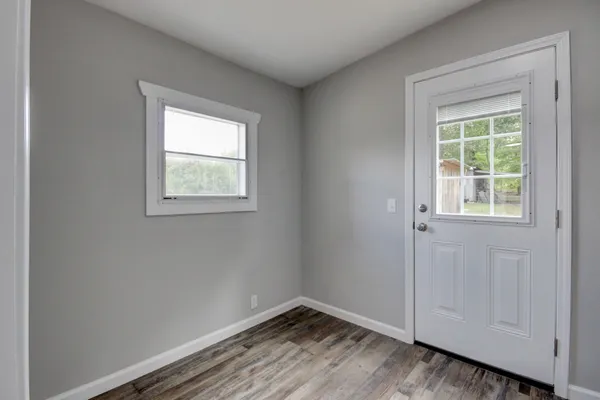 an empty room with wooden floor and window