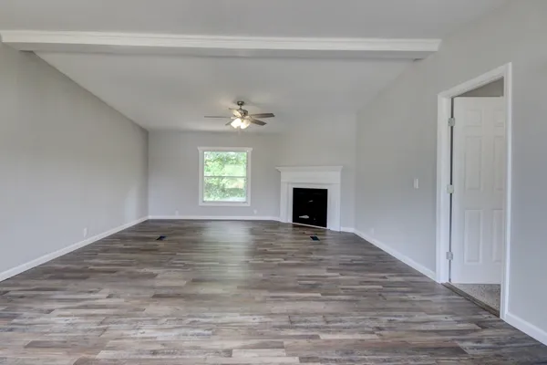 a view of an empty room with window and wooden floor
