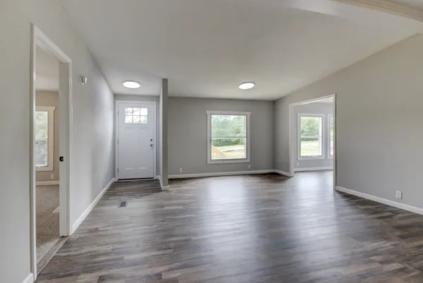 a view of an empty room and chandelier fan and fire place