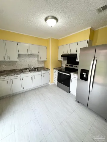 a kitchen with stainless steel appliances granite countertop a stove a sink and a refrigerator