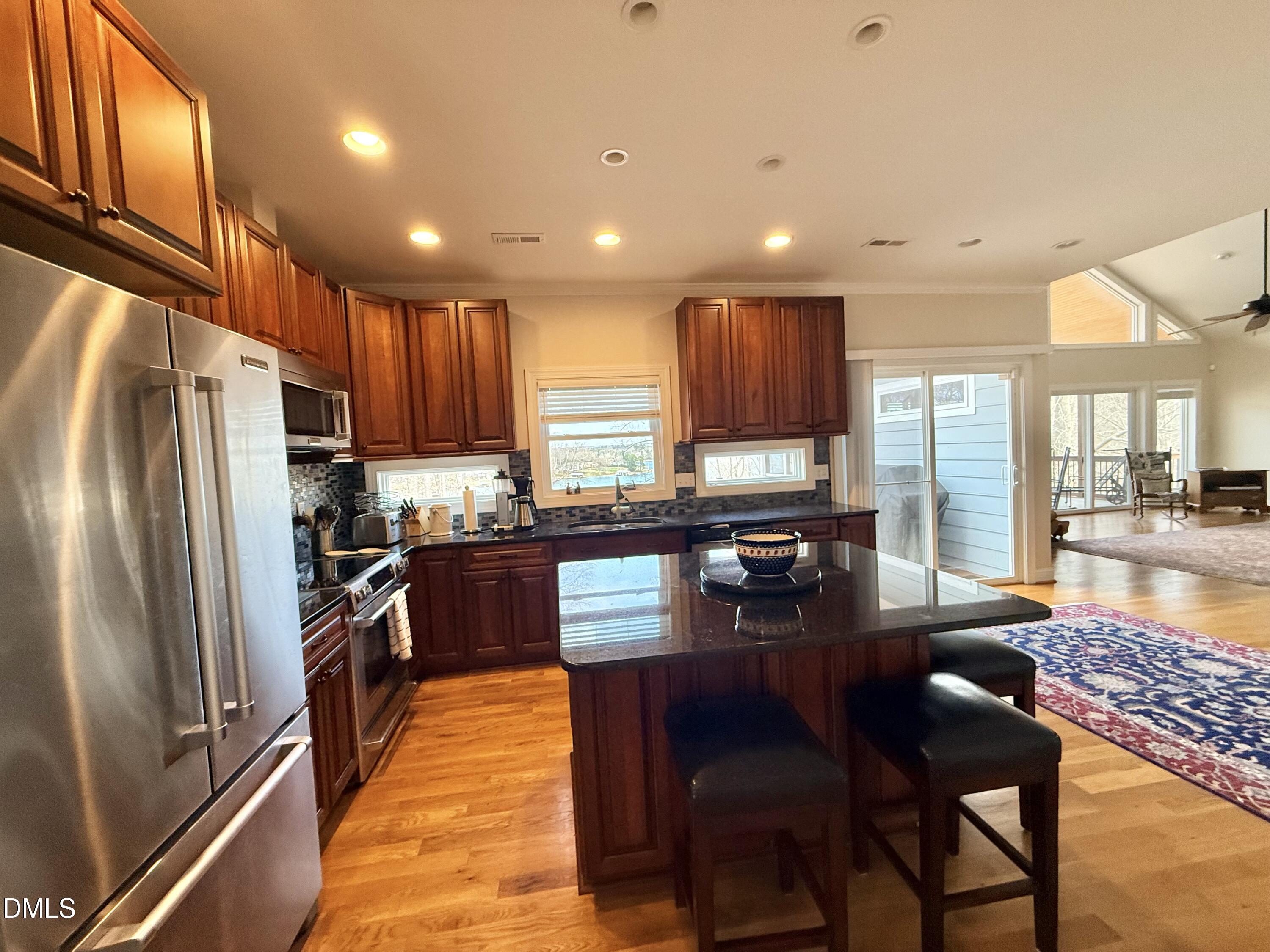 250 Bunny Rabbit Road Leasburg, NC 27291 - Photo 9 of 66 a kitchen with stainless steel appliances granite countertop a refrigerator a stove a sink a dining table and chairs with wooden floor