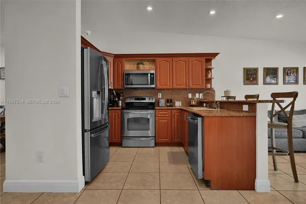 a kitchen with stainless steel appliances kitchen island granite countertop a stove a sink a table and chairs
