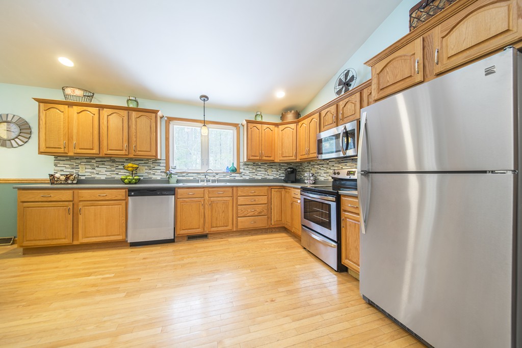 118 Wales Road Monson, MA 01057 - Photo 9 of 30 a kitchen with stainless steel appliances granite countertop a refrigerator a sink dishwasher a s stove top oven a dining table and chairs with wooden floor