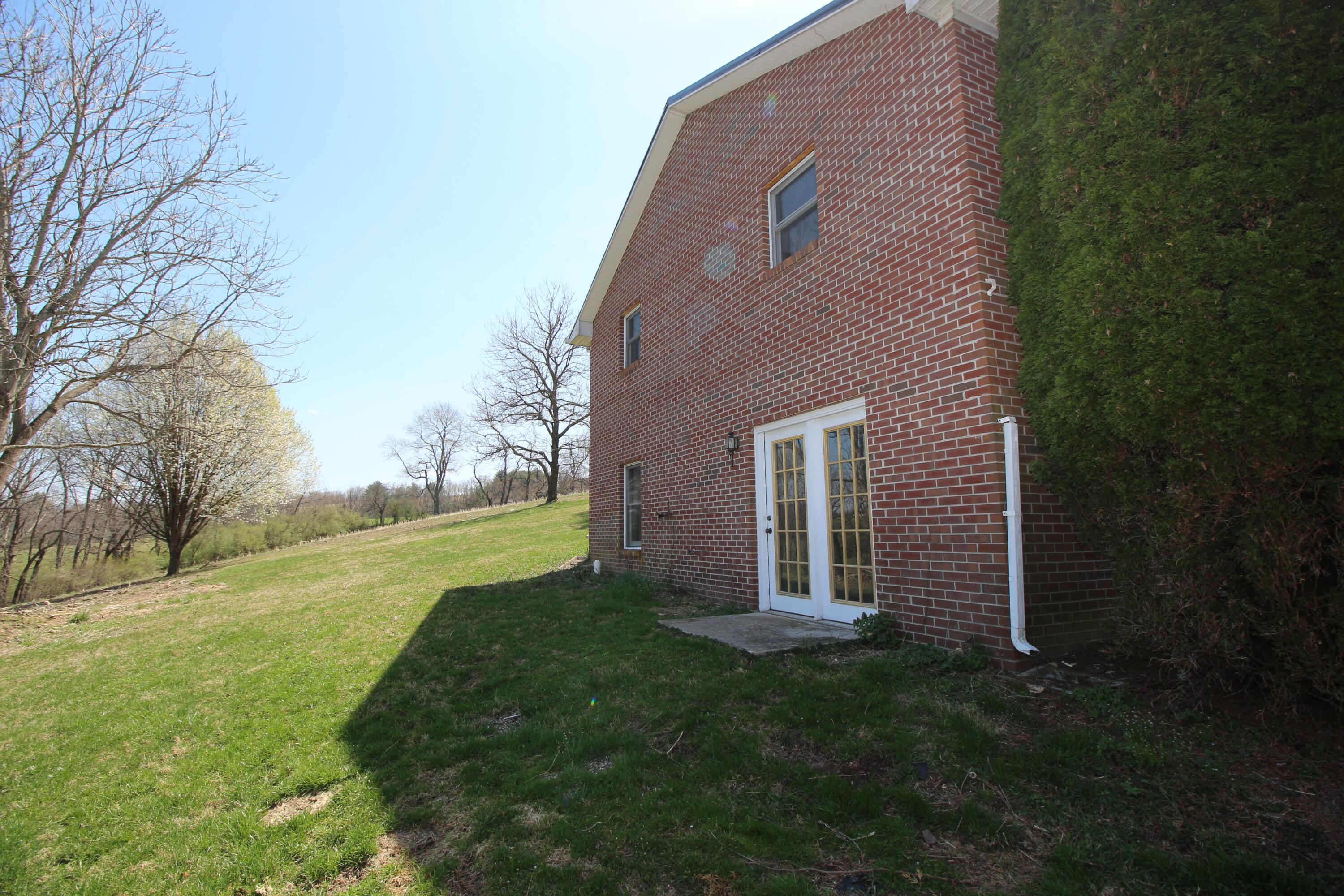 7080 Belspring Road Radford, VA 24141 - Photo 41 of 53 a brick house with a yard plants and large trees
