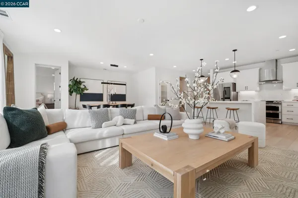 a living room with furniture kitchen view and a wooden floor