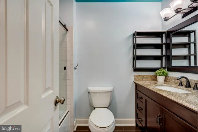 a bathroom with a granite countertop toilet sink and mirror