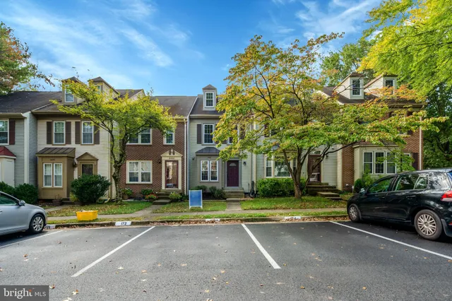 a view of a white house with a big yard and large trees