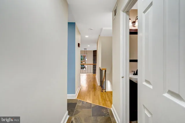 a view of a hallway with wooden floor and a bathroom