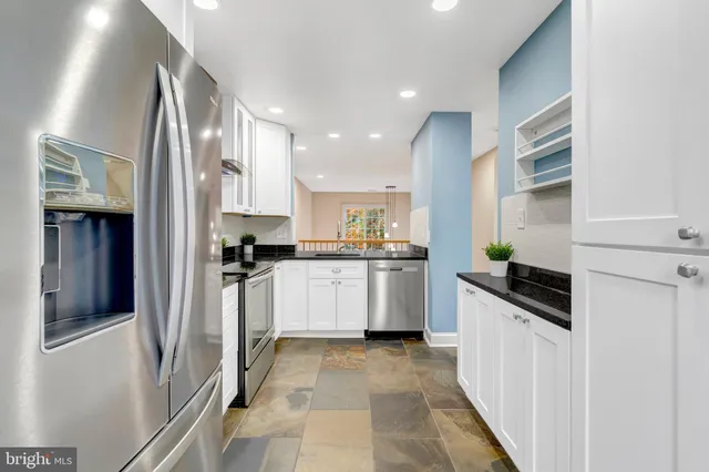 a kitchen with white cabinets and refrigerator