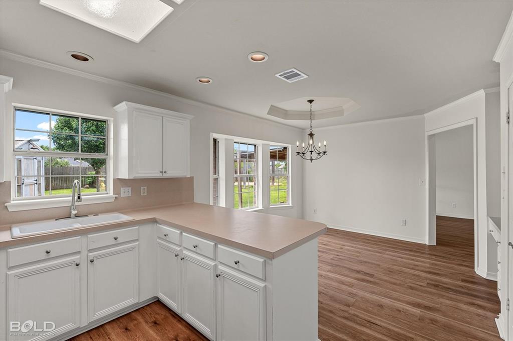 1962 Palmetto Road Benton, LA 71006 - Photo 14 of 40 The kitchen features white cabinetry, a sink with a window overlooking the backyard, and a light-colored countertop