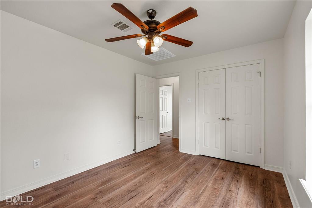 1962 Palmetto Road Benton, LA 71006 - Photo 24 of 40 This room features wood-look flooring, white walls, and a ceiling fan with integrated lighting