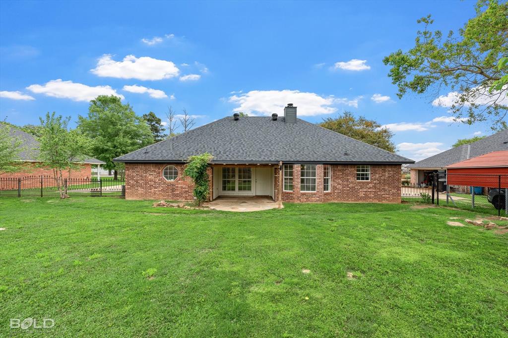 1962 Palmetto Road Benton, LA 71006 - Photo 28 of 40 The property features a brick exterior, a dark shingle roof, and a spacious green lawn