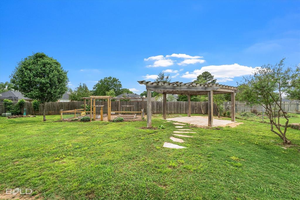 1962 Palmetto Road Benton, LA 71006 - Photo 30 of 40 Expansive yard featuring a wooden pergola with a paved patio, a stepping stone pathway, and a wooden fence