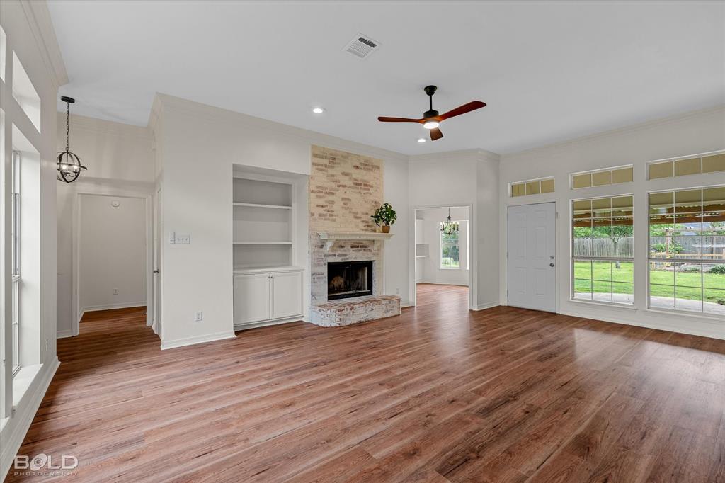 1962 Palmetto Road Benton, LA 71006 - Photo 3 of 40 Spacious living area featuring hardwood flooring, a brick fireplace with a mantle, and built-in shelving