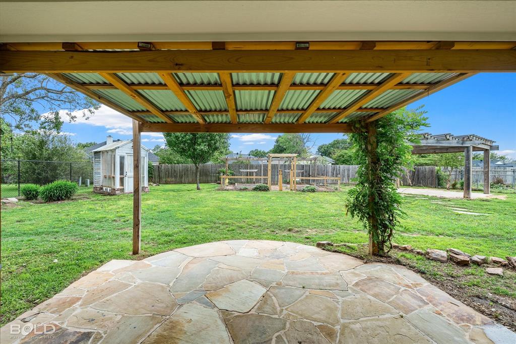 1962 Palmetto Road Benton, LA 71006 - Photo 31 of 40 The property features an outdoor patio with a flagstone surface, covered by a wood and corrugated metal pergola